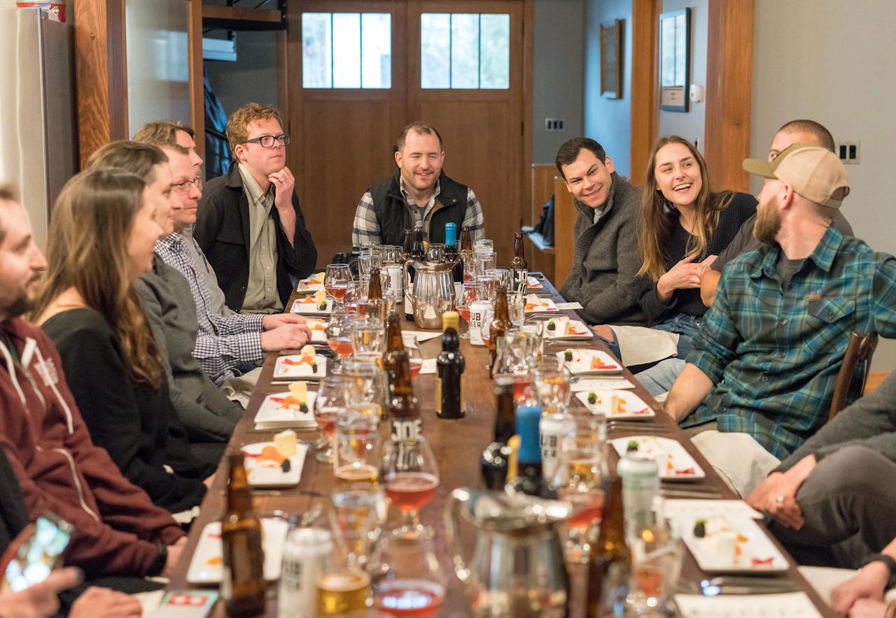 about-01 A joyful group of adults enjoying a meal and drinks at a restaurant, fostering communication and friendship.